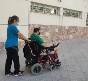 persona en silla de ruedas dando un paseo con ayudante