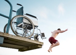 Fotografía de prevención de lesión en el verano, se ve una persona que ha dejado su silla para tirarse desde una plataforma a una piscina